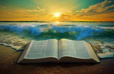 Close up of ocean waves at sunrise with a Bible